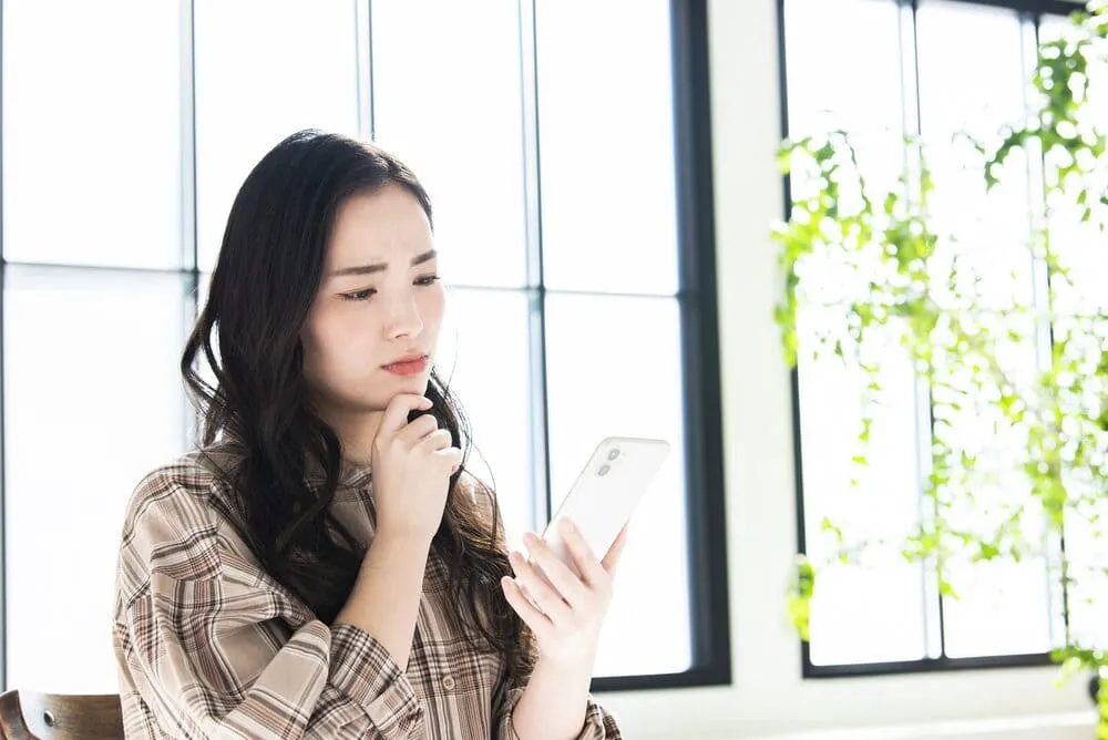 スマホを見て悩む女性