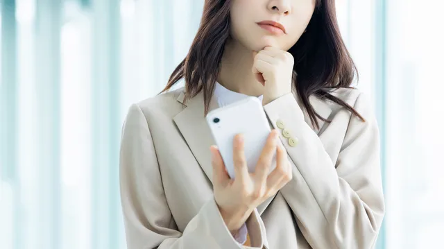 スマホを持って悩む女性