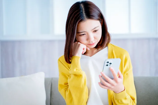スマホを見ながら悩む女性