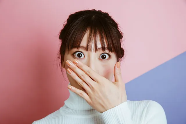 驚いて顔を隠す女性