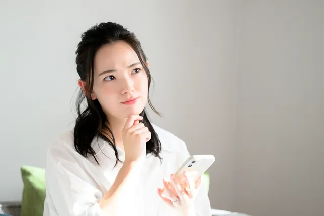 スマホを持って悩む女性