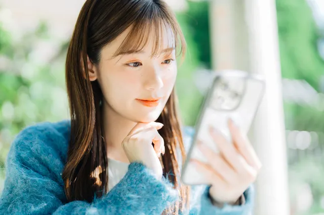 スマホを見ながら考える女性