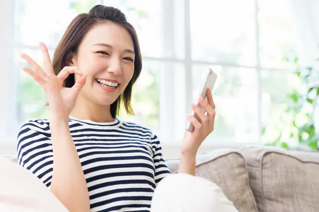 スマホを持ってOKサインを出す女性